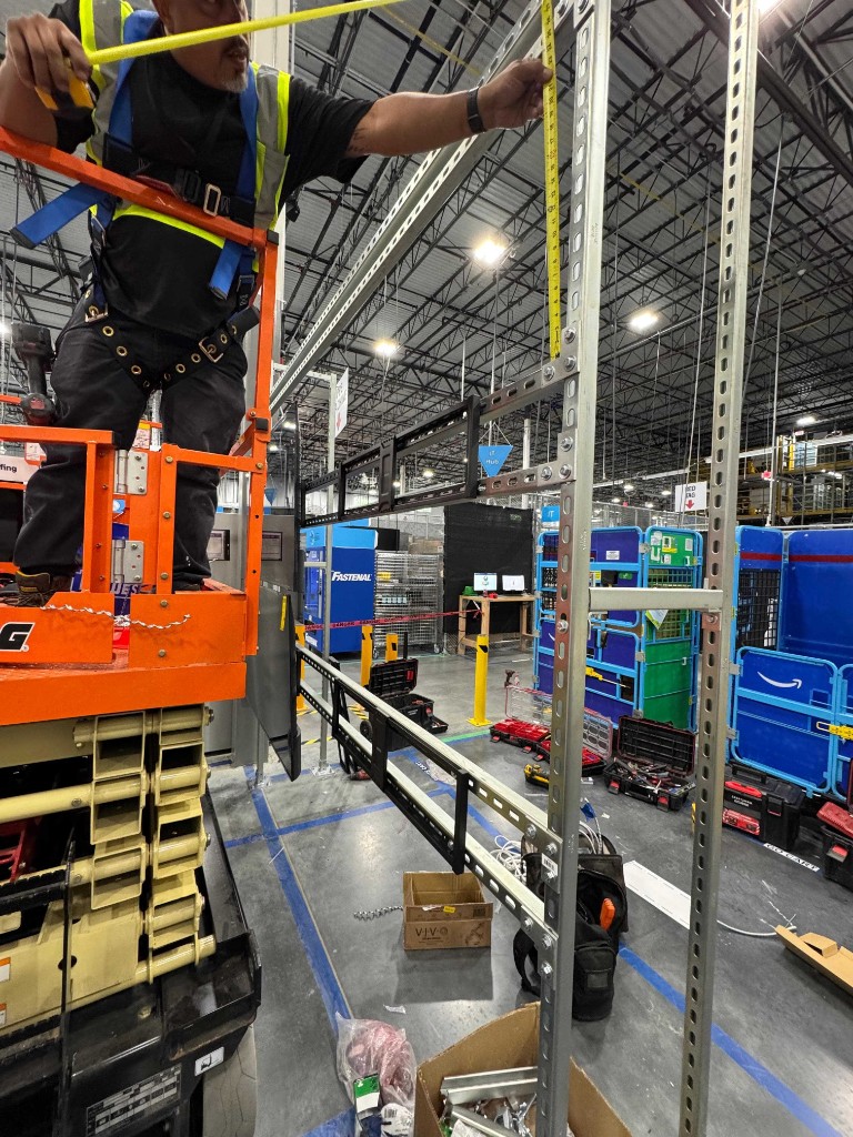 Technician measuring warehouse installation supports